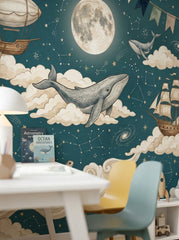 Close-up of illustrated whale wallpaper with dark teal sky, glowing moon, stars, constellations and nautical adventure details.