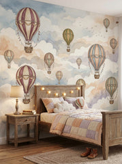 Vintage hot air balloon wallpaper mural with pastel watercolor clouds behind a wooden kids bed in a cozy bedroom.