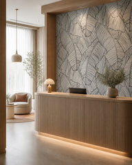 Black and white banana leaves wallpaper at a hotel reception desk.