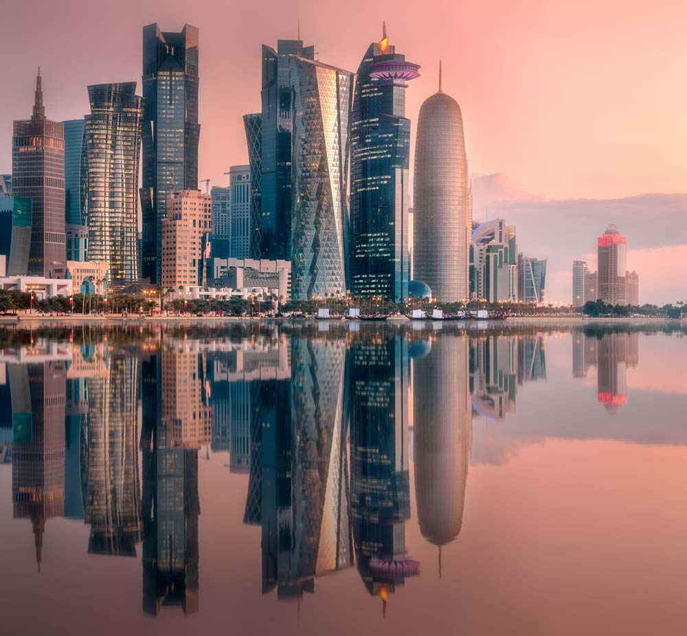 Nowoczesna panorama Doha o zachodzie słońca Naklejka - Odblaskowe drapacze chmur na wodzie