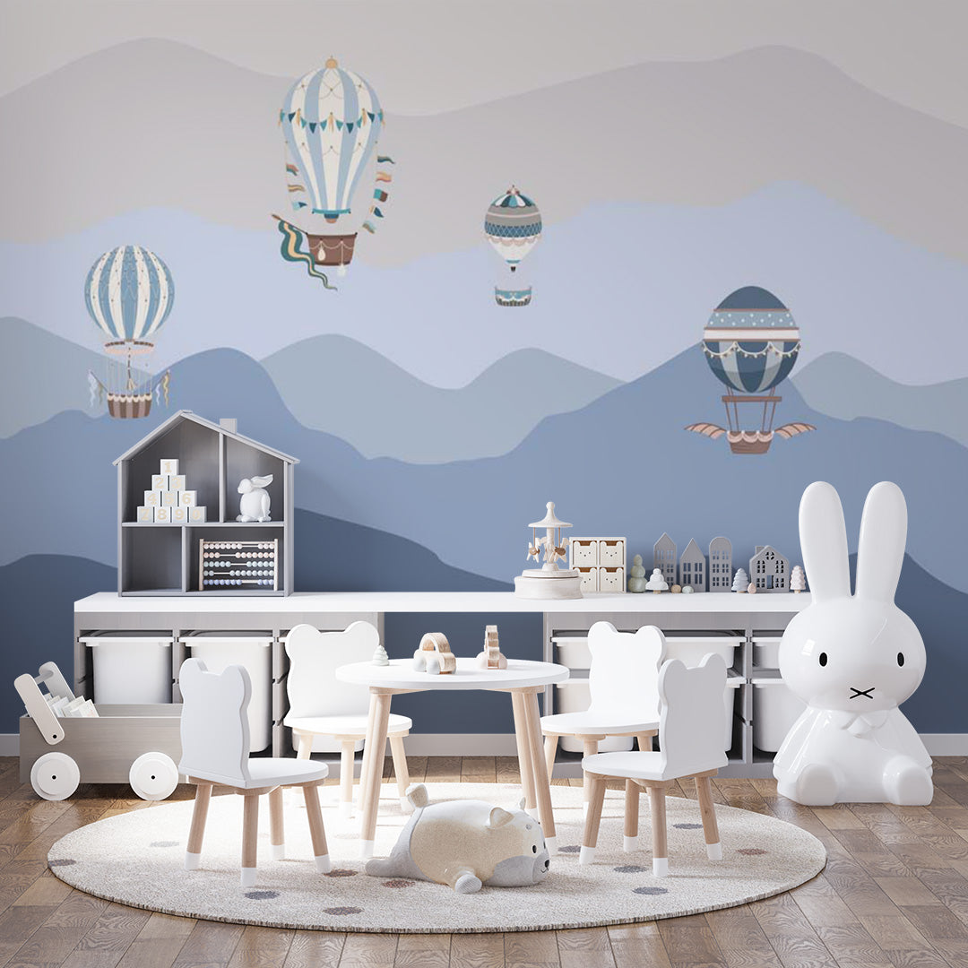 Blue kids room wallpaper with ornate vintage hot-air balloons floating above layered mountains in navy, slate, gray, and cream.