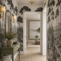 Black and white Italian landscape wallpaper in an entry hall with arched mirror and green console.