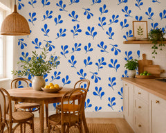 Blue leaf wallpaper used above white bathroom wall tiles with wood vanity and black framed mirror.