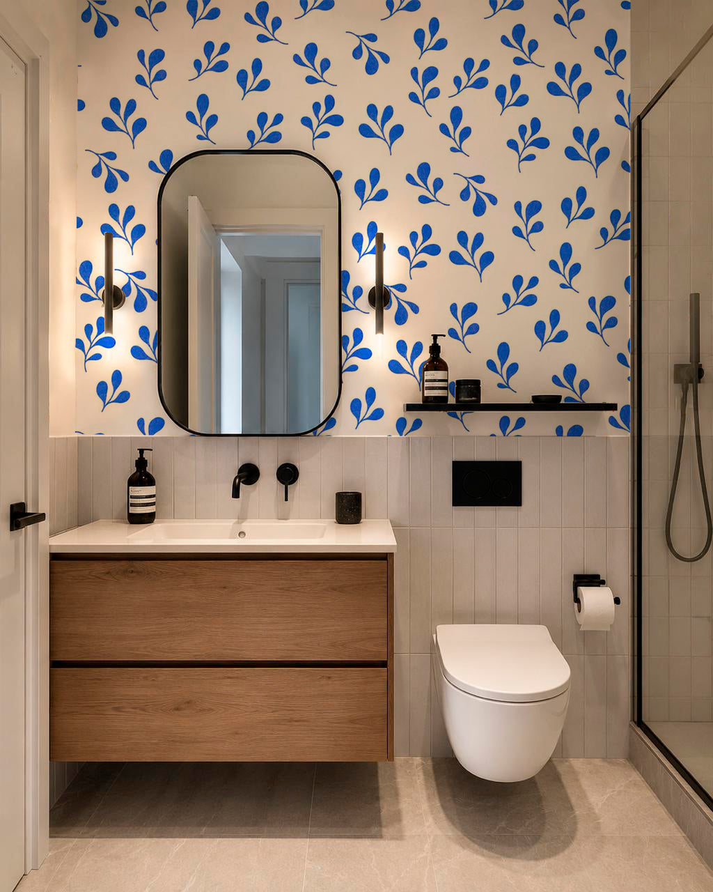 Bold blue botanical wallpaper decorating a traditional staircase with wood railing and framed artwork.