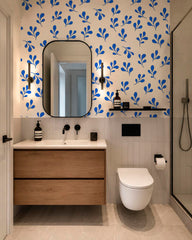 Bold blue botanical wallpaper decorating a traditional staircase with wood railing and framed artwork.