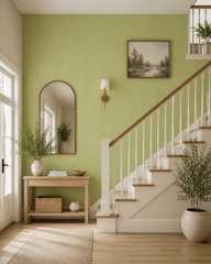 Pistachio green textured wallpaper in a staircase hall with arched mirror.