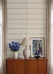 Cream tile effect wallpaper close-up behind a vintage sideboard with lamp and blue flowers.