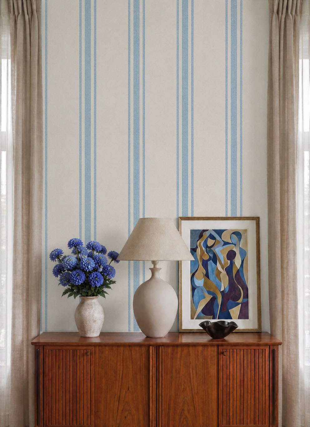 Blue and cream stripe wallpaper close-up behind a vintage sideboard with lamp and blue flowers.