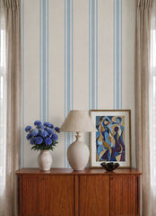Blue and cream stripe wallpaper close-up behind a vintage sideboard with lamp and blue flowers.