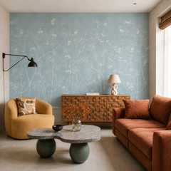 Dusty blue chinoiserie blossom wallpaper in a modern living room with orange sofa and sculptural table.