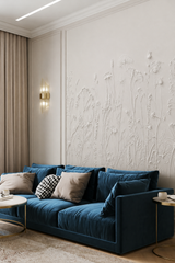 White 3D effect wildflower wallpaper behind a navy velvet sofa in a living room.