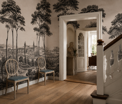 Black and white Italian toile wallpaper in a hallway with staircase and chairs.