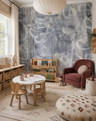 Grey music notes wallpaper in a playroom with a round table and a burgundy armchair.