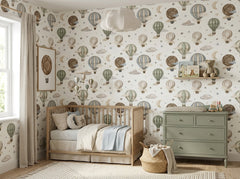 Vintage balloon nursery wallpaper displayed behind a wooden baby crib with sage green dresser and neutral decor.