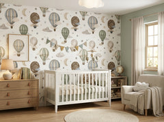 Watercolor hot air balloon wall mural shown in a soft neutral baby room with white crib and cozy armchair.