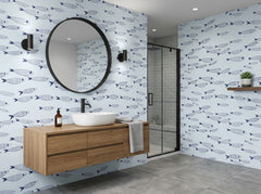 Coastal blue fish wallpaper decorating a bright bathroom with white sink, wood cabinet and grey tile floor.
