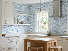 Light blue nautical wallpaper with repeating fish design in a bright modern kitchen with wood island.