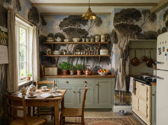 Moody pine forest wallpaper in a cottage kitchen with open shelves.