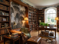 Moody pine forest wallpaper in a library study with chesterfield sofa.