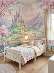 Pink fairytale castle wallpaper in a girl’s bedroom with a white toddler bed and a pastel quilt.