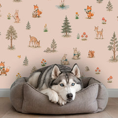 Close-up of woodland animals wallpaper with deer, rabbits, foxes, squirrels, mushrooms, flowers and forest trees on a blush beige background.